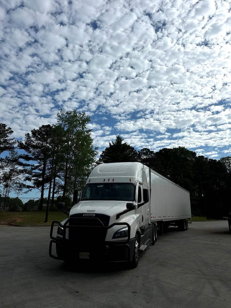 Front view of a white SDS UZ semi-truck under a cloudy sky